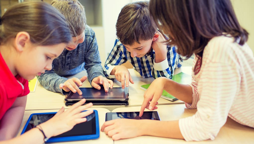 Elementary students having fun playing online games on tablets Feature Image