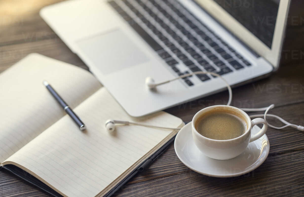 Earbuds with notebook and coffee near laptop stock photo